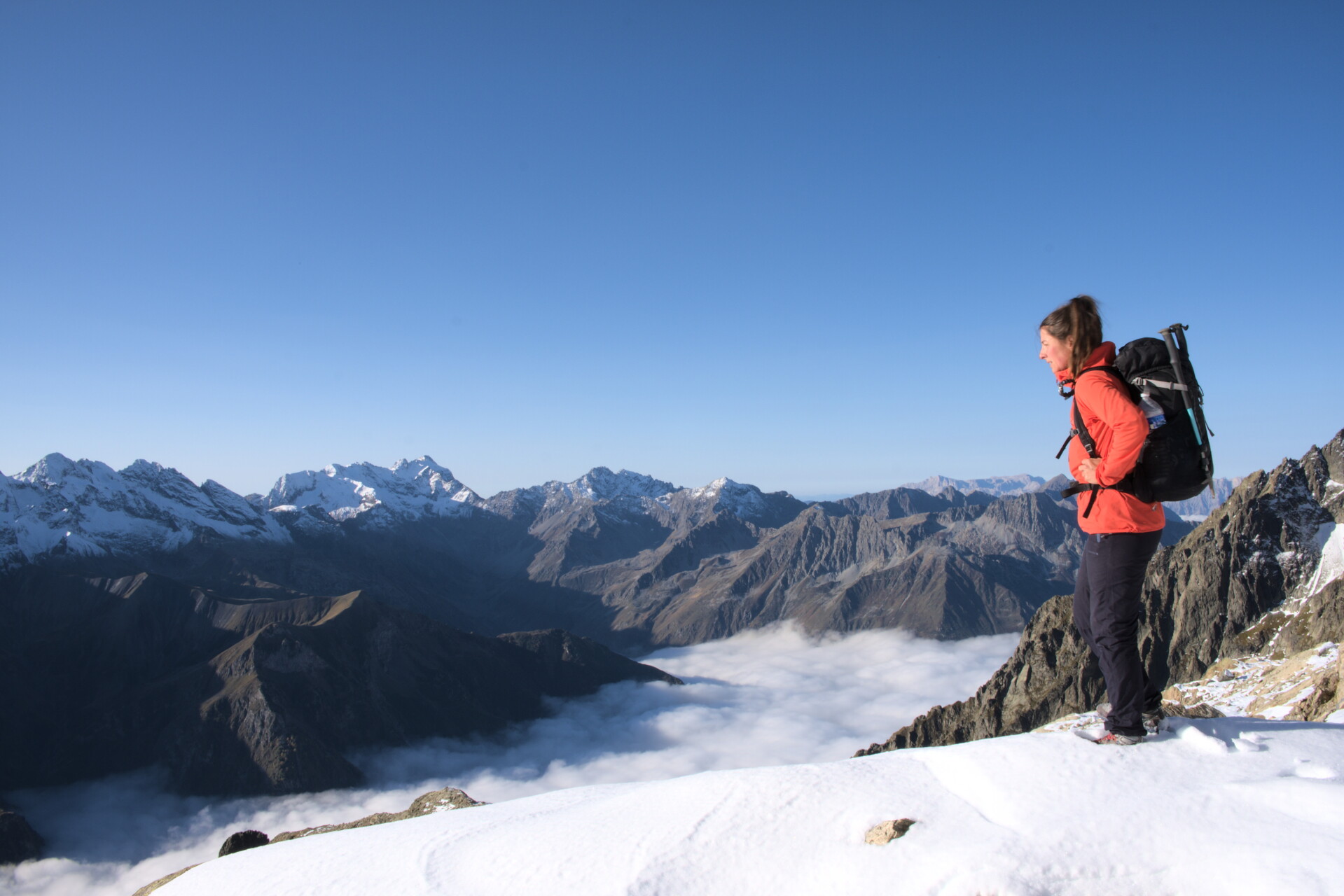 Hiker on a ridge above a sea of cloud, Valgaudemar